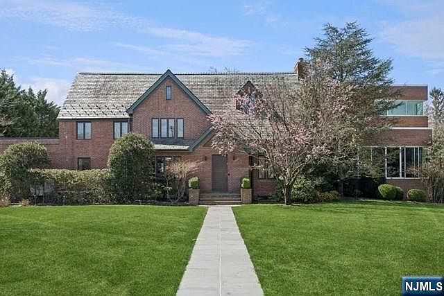 The full Tudor elevation of 532 Winthrop seen from the front lawn, brick walls, steep green gables, and a wide manicured yard set back from the street